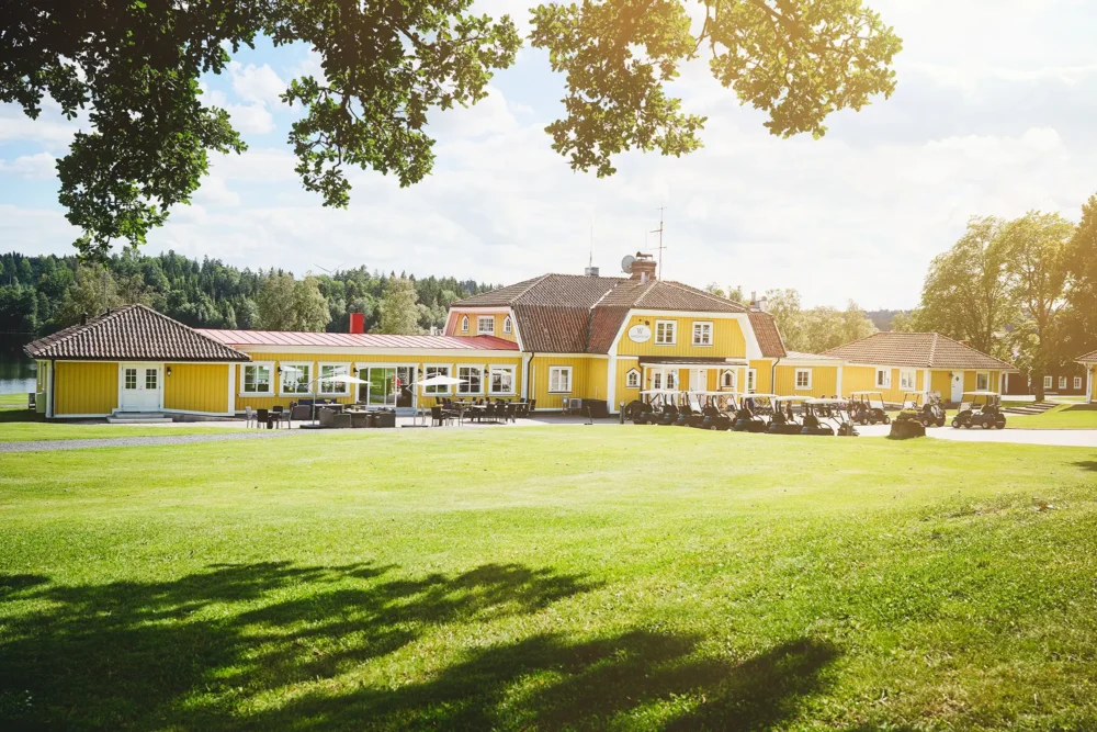 Wiredaholm, vår huvudbyggnad, golfbilar och gräsmatta i vår solen.