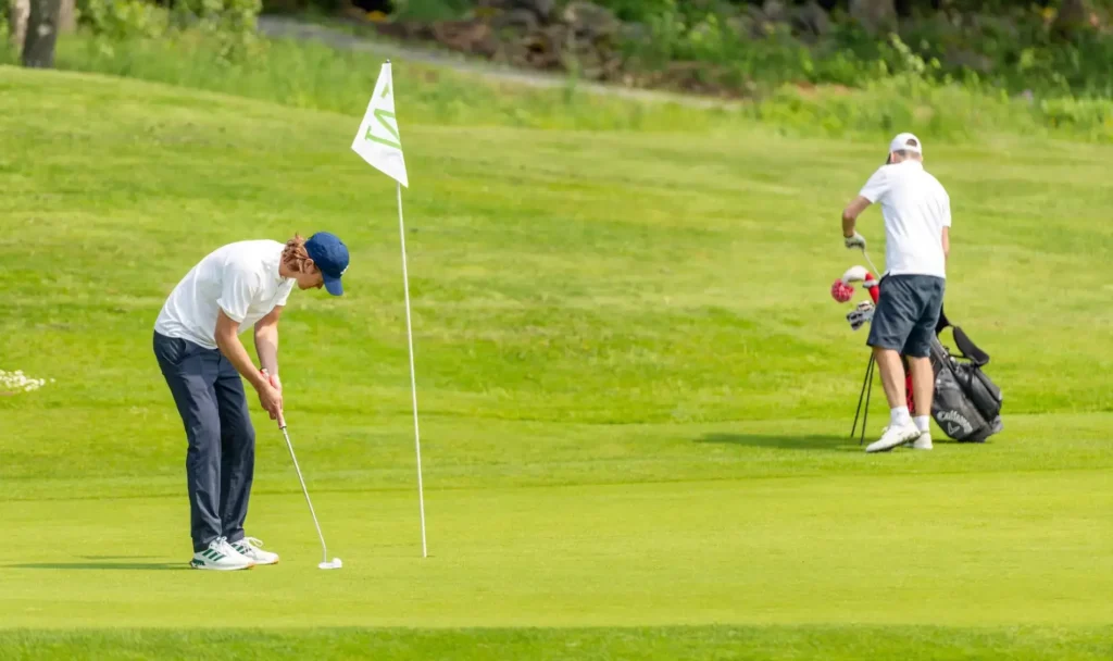 Två golfare står på greenen vid flaggan på golfbanan.